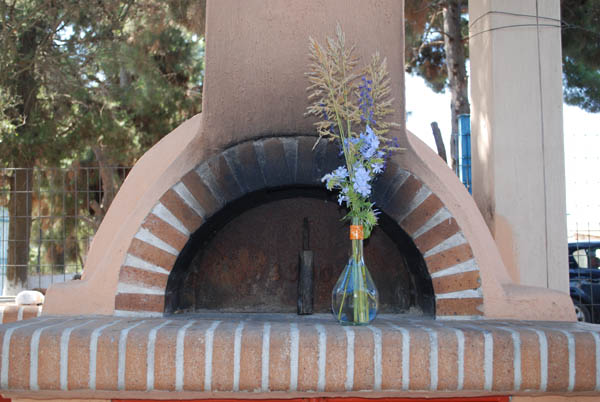 Το πρωτότυπο βάζο με τα αγριολούλουδα μπροστά από τον ξυλόφουρνο Το πρωτότυπο βάζο με τα αγριολούλουδα μπροστά από τον ξυλόφουρνο